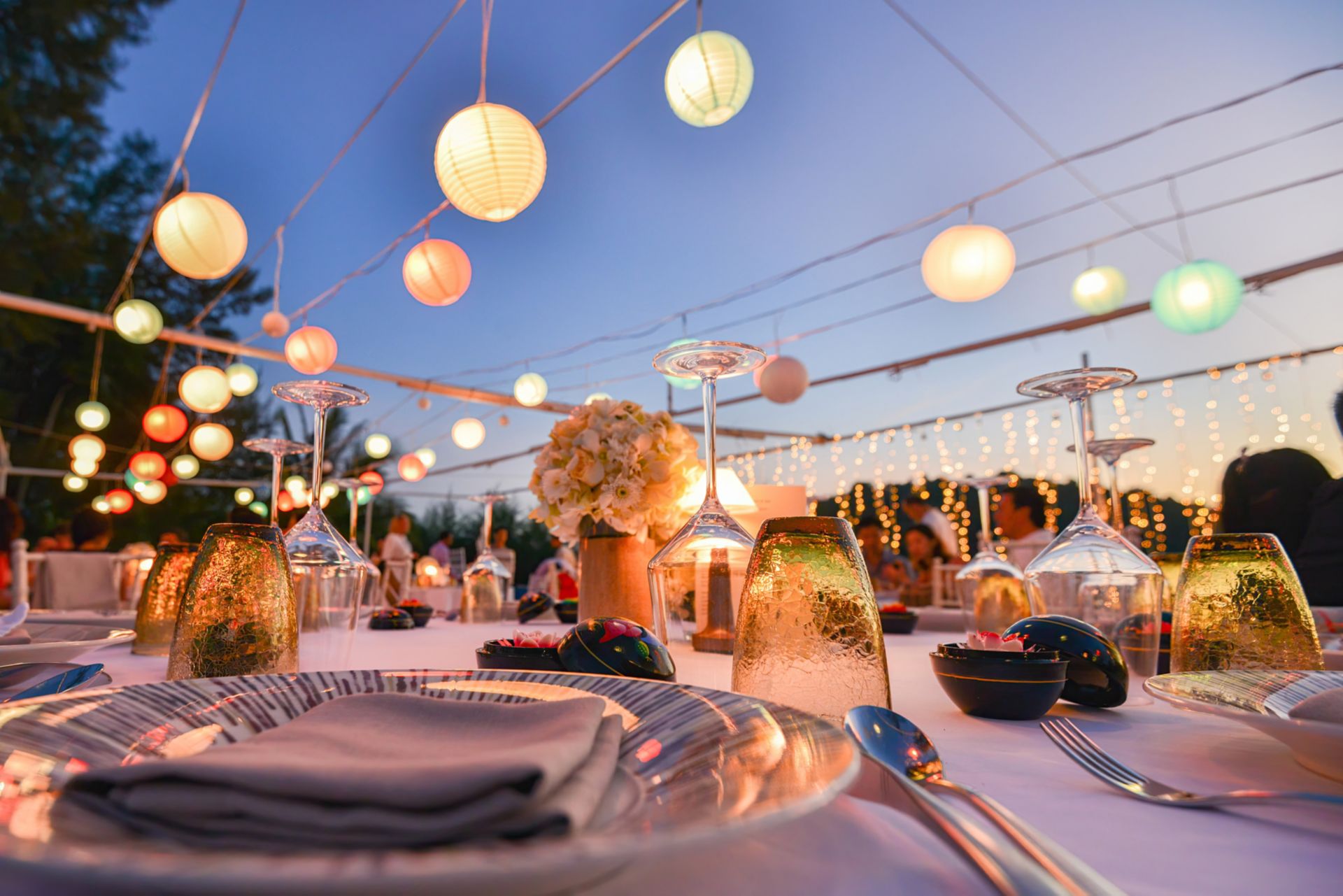 Outdoor evening event with lanterns and banquet tables
